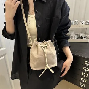 Minimalist beige drawstring bucket bag featuring a subtle glitter texture and gold hardware