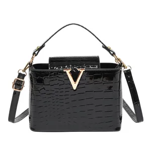 Fashionable black crocodile embossed handbag with gold V-shaped buckle and strap