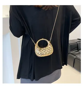 Detailed view of golden crescent handbag with quilted texture and metal chain strap