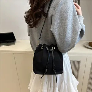 Minimalist black bucket bag with drawstring closure and leather strap in lifestyle setting