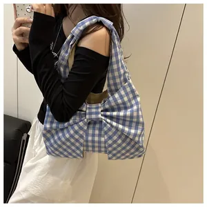 Detail of blue and white checkered tote bag with large bow and wide shoulder straps