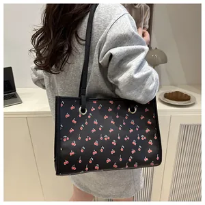 Détail du sac cabas noir en cuir avec imprimé cerises porté par un mannequin chic