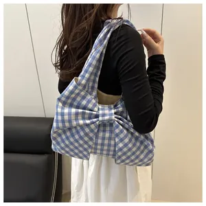 Close-up of blue gingham shoulder bag featuring a large bow detail and soft cotton fabric