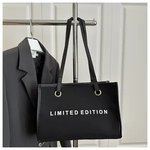 Black canvas tote bag featuring white LIMITED EDITION lettering and slim leather straps