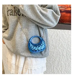 Close-up of bright blue glossy crescent bag with diamond quilted texture and gold chain