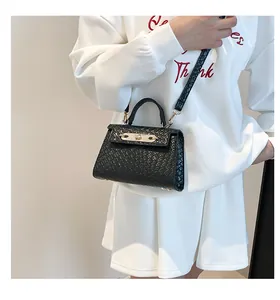 Détail d'un mini sac bandoulière noir à texture tressée avec boucle dorée sur modèle