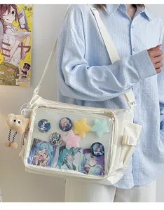 Detail of white ita bag with large transparent PVC window, badges and plush star decor