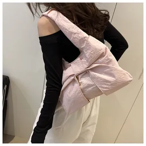 Detailed view of pink bow-shaped shoulder bag featuring soft pleated texture and wide strap