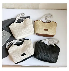 Detail of four woven straw tote bags with cotton rope handles and leather patch on white bedding