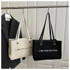 Detail of canvas tote bag featuring limited edition text and metal eyelet accents