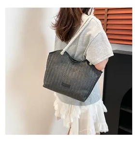Close-up of black woven tote bag with V-pattern texture and white rope handles
