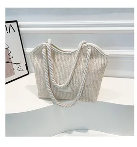 Detail of hand-woven straw tote bag texture with cotton rope handles and logo patch