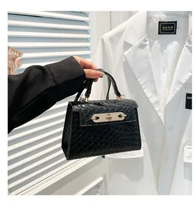 Détail d'un mini sac noir avec texture tissée et fermoir doré tenu par un mannequin