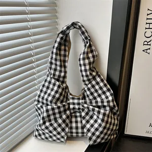 Gingham bow-shaped shoulder bag with knot handle in a minimalist interior setting