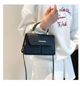 Dettaglio della mini borsa nera con finiture dorate e manico a corda intrecciata