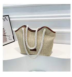 Detail of hand-woven straw tote bag with brown leather tag and thick cotton rope handles