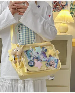 Detail of yellow canvas itabag with clear PVC window showing anime badges and plushies