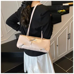 Close-up of a cream baguette bag with silver bows and double thin shoulder straps