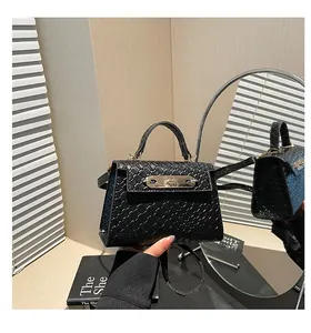 Detail of black woven texture handbag with silver twist lock reflected in a mirror