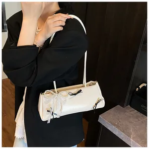 Detail of cream baguette bag featuring pearl lace bow and black ribbon accents
