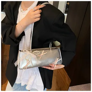 Silver baguette bag detail with pink ribbon bows and pearl lace pendant on the shoulder