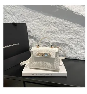 Close-up of white woven leather handbag with golden lock and hardware detailing
