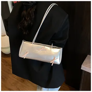 Silver metallic shoulder bag detail featuring pink ribbon bows and long thin strap
