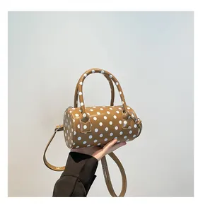 Detailed close-up of brown polka dot barrel bag with dual handles and metal hardware