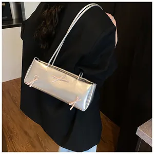 Detail of silver baguette bag with pink ribbon bows worn by model in black blazer