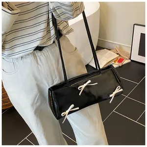 Close-up of black glossy shoulder bag with white bows in a creative lifestyle setting