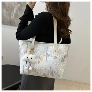 Detalle del bolso acolchado blanco con bordados de colores y colgante de peluche