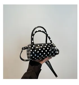 Detailed view of the retro polka dot cylinder handbag with glossy leather finish and silver hardware