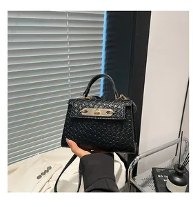 Detail of black woven texture handbag with gold twist lock and elegant handle