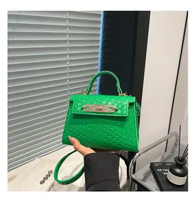 Detailed side view of green woven leather Kelly bag with gold lock and shoulder strap