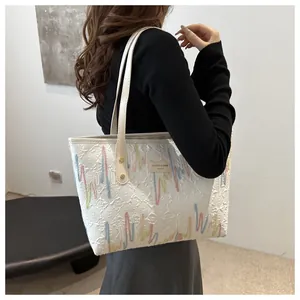 Detalle del bolso tote blanco con bordados de colores y etiqueta de cuero suave