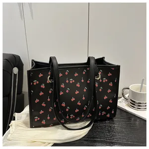 Détail du sac cabas noir à imprimé cerises avec anneaux métalliques sur fond lifestyle