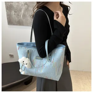 Detalle del bolso tote de rayas azul claro con bordado y colgante de nube de felpa