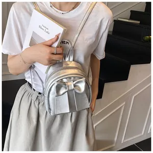 Mini sac à dos argenté avec grand nœud porté par un mannequin en style décontracté