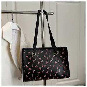 Détail du sac cabas à imprimé cerise avec poignées en cuir PU noir et anneaux dorés