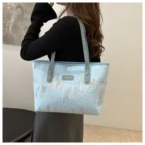 Detalle de bolso tote azul acolchado con bordados coloridos y parche de cuero
