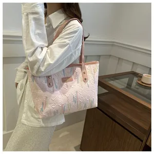 Detalle del bolso tote a rayas rosas con bordados coloridos y parche del logo