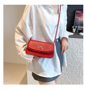 Detail of red shoulder bag with gold metal bow on smooth faux leather surface