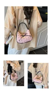 Détails du sac croissant rose avec motifs de nœuds et pendentif cœur doré élégant