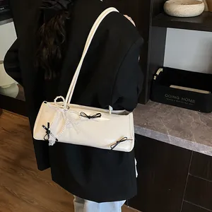 Creamy white patent leather baguette bag with black bows and pearl chain detail
