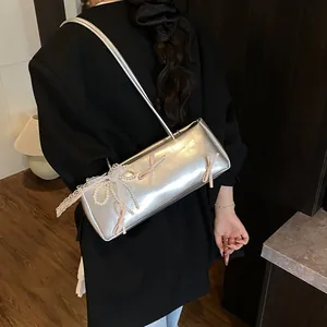Silver baguette bag with lace, heart pearls, and pink bows shown on model shoulder