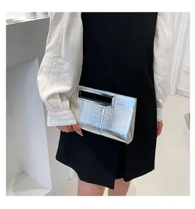 Detail of silver crocodile pattern clutch bag with rectangular metal cutout handle