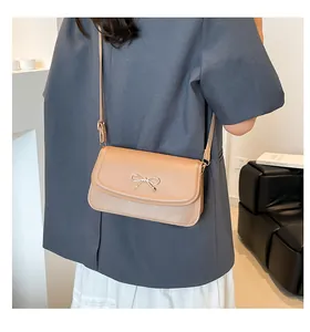 Detail of light brown shoulder bag with a metal bow buckle and adjustable strap