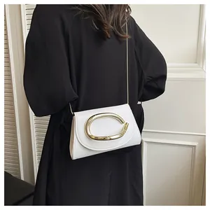 Detail of white leather crossbody bag with gold C-shaped buckle on black dress