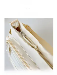 Close-up of smooth double zipper closure with woven pullers on a beige canvas tote bag