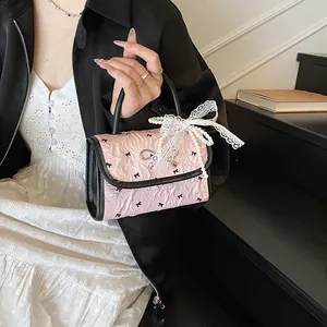 Pink pleated handbag with black bow prints and lace detail held by a model